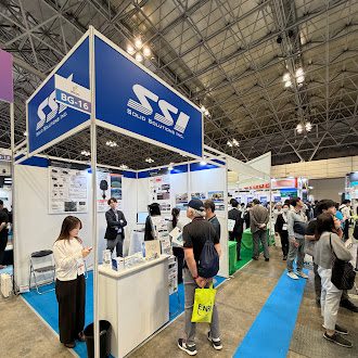 社名ロゴの看板を掲げた自社ブースと、通路を行き交う来場者
